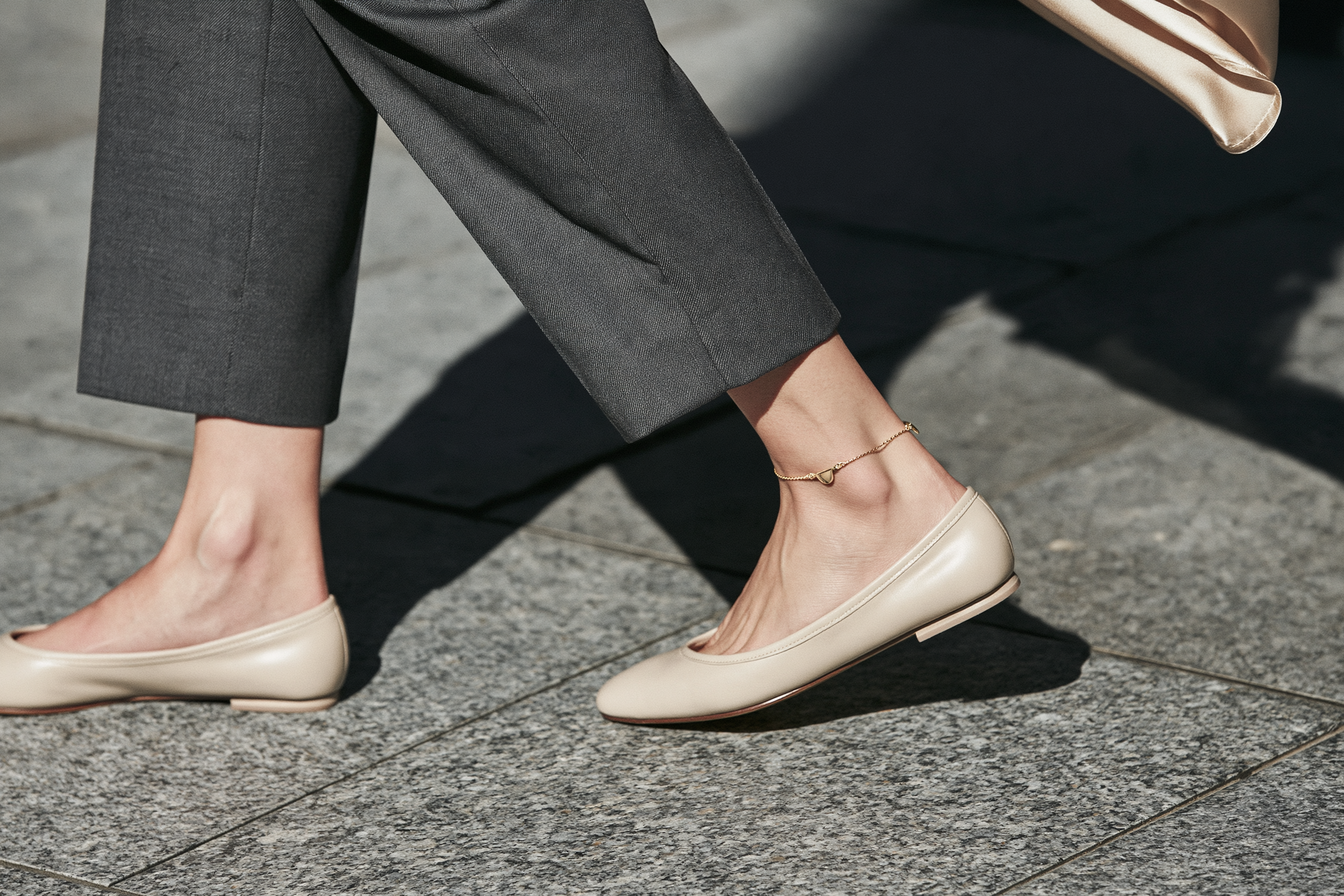 Minimal gold anklet styled with white sneakers in a contemporary city look